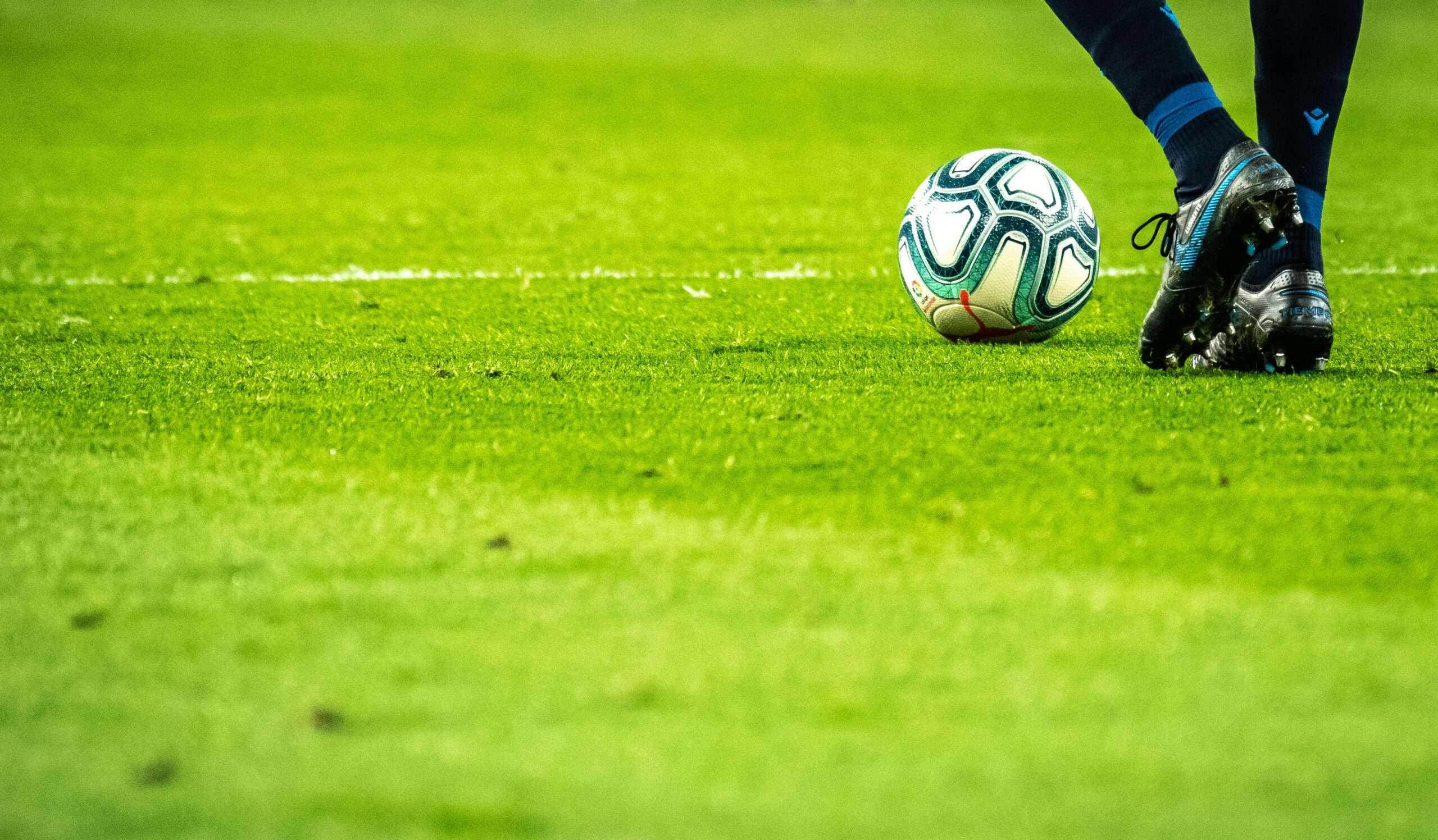 Fußball und Füße eines Spielers auf dem Rasen