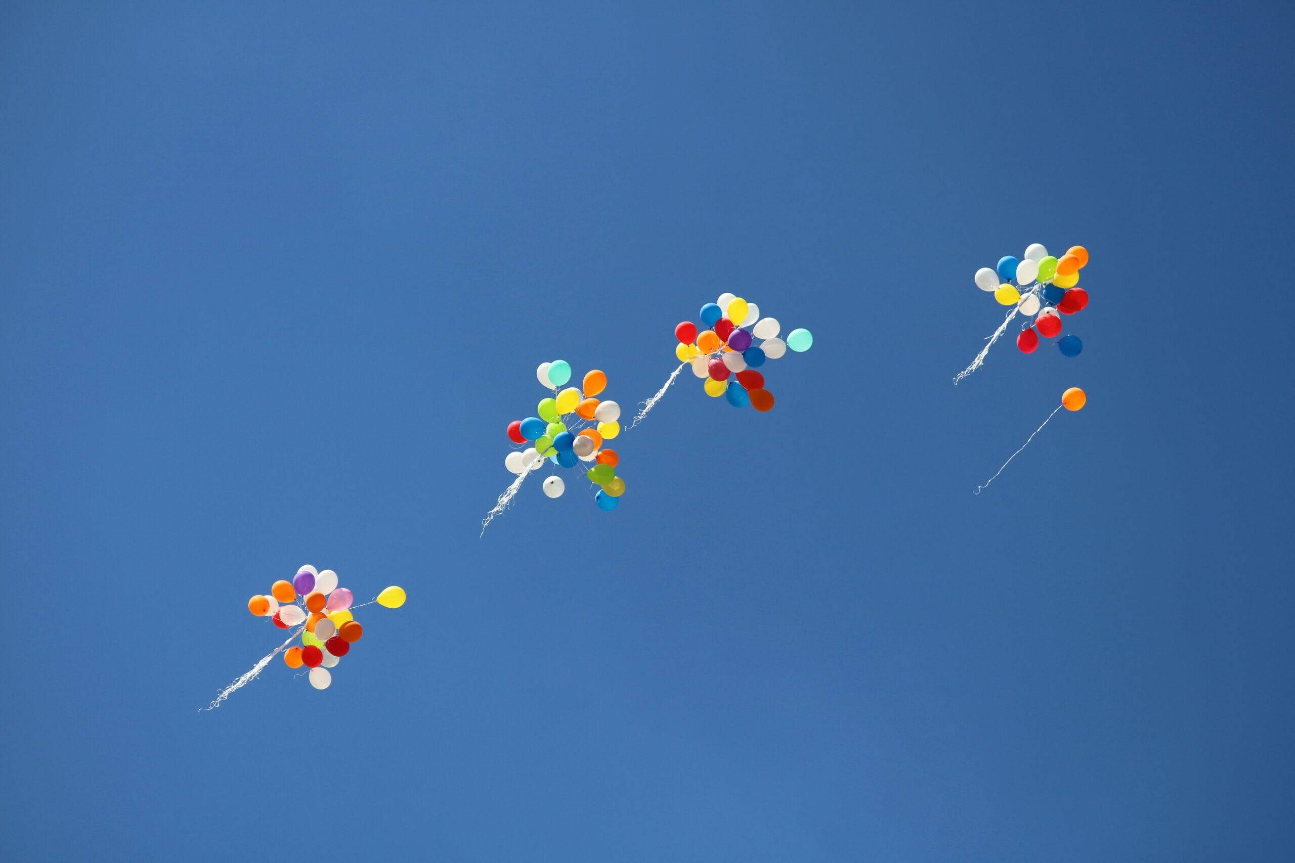 viele verschiedene bunte Luftballons die im Himmel fliegen
